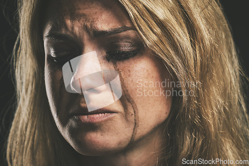 Image of Sad, depression and woman crying on dark studio background for mental health or psychology awareness. Young, depressed mental illness person tears and smudge makeup for anxiety, violence or fear
