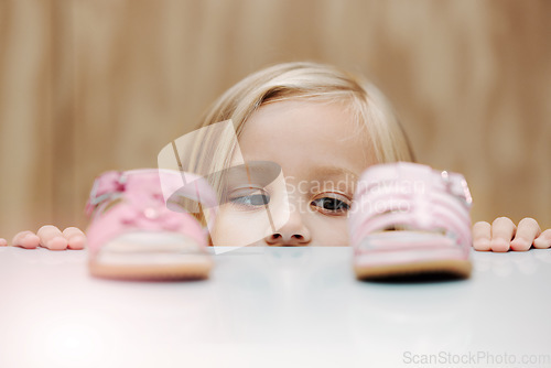 Image of Kids, fashion and shoes with a girl choosing between footwear while shopping in a retail store. Children, cute and choice with a young female child deciding what shoe to buy for her home wardrobe