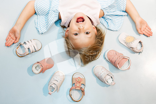 Image of Child, shoes and head above floor with smile on face against blue backdrop. Girl, happy and sandal in mockup excited with happiness, color and summer fashion against studio background in Sweden