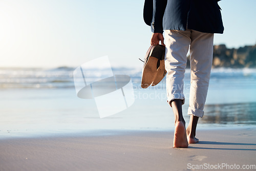 Image of Walking, beach and mental heath with a business man walking in the sand by the sea or ocean after work. Water, nature and freedom with a male employee taking a walk on the coast during summer
