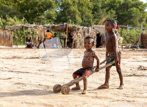 Image of Boys have fun with a simple toy on wheels at the ferry port in Bekopaka. Madagascar