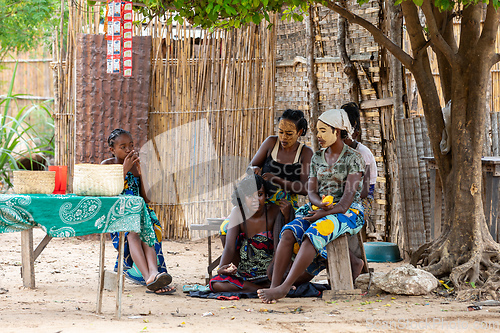 Image of Malagasy woman hairstyling in front of her hut resting in shaddow. Bekopaka, Madagascar