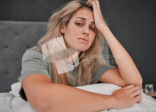 Image of Depression, tired and portrait of a sick woman sitting on the bed in her bedroom at home. Anxiety, mental health problem and exhausted girl crying with insomnia, headache and burnout at her house.