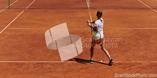 Image of A young girl showing professional tennis skills in a competitive match on a sunny day, surrounded by the modern aesthetics of a tennis court.