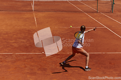 Image of A young girl showing professional tennis skills in a competitive match on a sunny day, surrounded by the modern aesthetics of a tennis court.