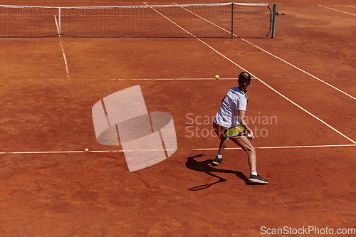 Image of A young girl showing professional tennis skills in a competitive match on a sunny day, surrounded by the modern aesthetics of a tennis court.