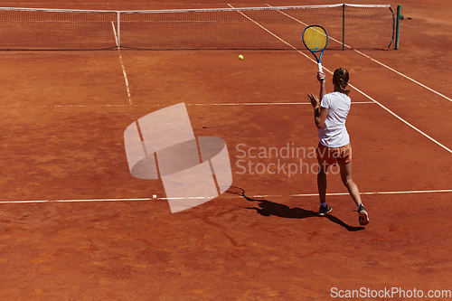 Image of A young girl showing professional tennis skills in a competitive match on a sunny day, surrounded by the modern aesthetics of a tennis court.