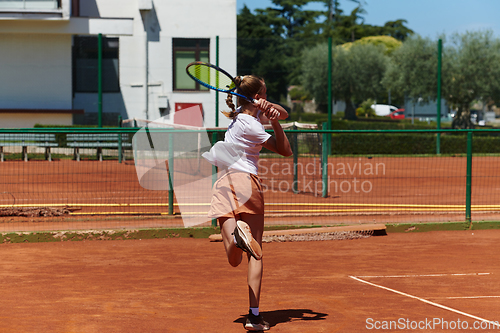 Image of A young girl showing professional tennis skills in a competitive match on a sunny day, surrounded by the modern aesthetics of a tennis court.