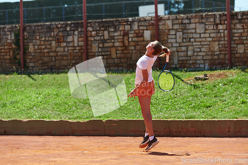 Image of A young girl showing professional tennis skills in a competitive match on a sunny day, surrounded by the modern aesthetics of a tennis court.