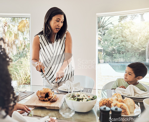 Image of Grandmother talking to children in dining room, food ready for dinner and share family home recipe in Mexico. Elderly woman cutting chicken on table, eat healthy together and grandma with hungry kids