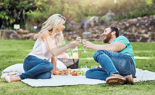 Image of Couple, picnic and park of a man and woman cheers to happiness and love in nature. Happy people together with a smile enjoying alcohol and food laughing with quality time for an anniversary outdoor