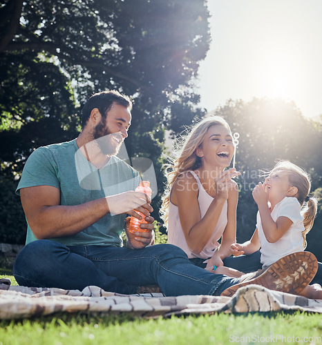 Image of Family, happy and bubbles with picnic in park together for summer, relax and nature. Smile, spring and peace with parents playing with girl in countryside field for youth, lifestyle and happiness