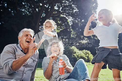 Image of Grandparents, bubbles and children play in park happy together for fun, joy and outdoor happiness. Retired, smile and excited elderly senior couple, girl grandkids and love playing outside in nature