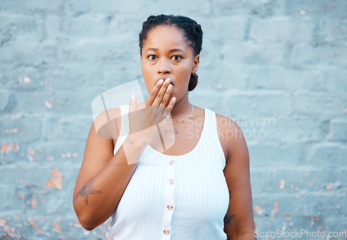 Image of Shocked black woman, hand and worry in silence for secret against a wall background. Portrait of African American female covering mouth in concerned facial expression for gossip, news or emoji