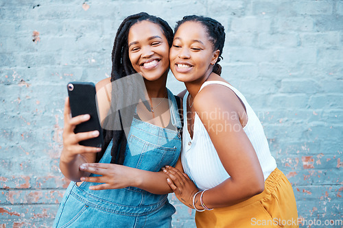 Image of Black women, friends and selfie while smiling and happy outside against city or urban wall and posing for friendship social media picture outside. African females or sisters with 5g network connectio