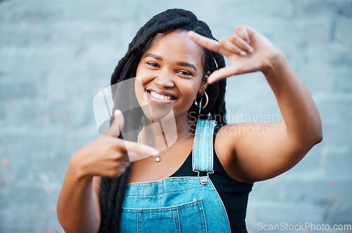 Image of Black woman, hands and finger frame showing smile, happiness and face against city building wall, mockup space or outside in Atlanta. Portrait of female model with fun or playful gesture for beauty