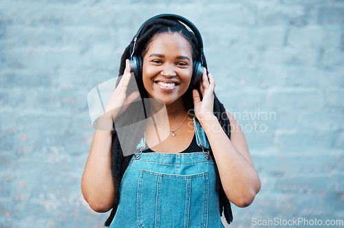 Image of Gen z black woman, music headphones and portrait on wall background in Nigeria city listening to radio, audio and sound. Happy young african girl student, freedom and streaming urban outdoor podcast