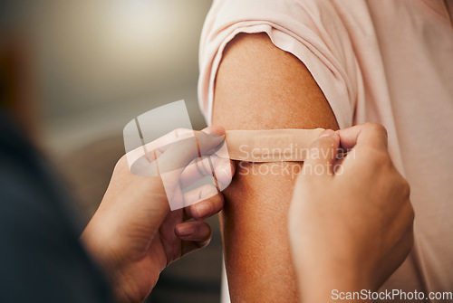 Image of Covid, vaccine and plaster with a doctor and patient consulting in an appointment or checkup at home. Nurse, healthcare and trust with a health professional using a bandaid on an arm after medication