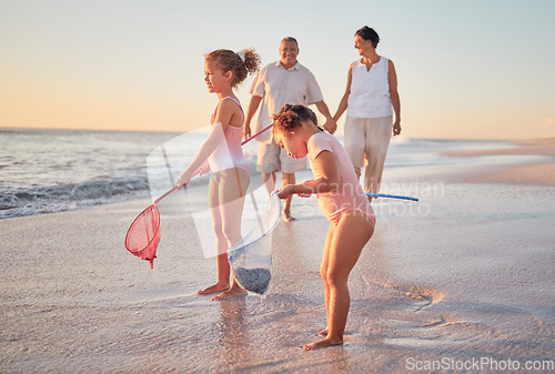 Image of Grandparents and children at the beach with fishing nets and having fun. Young kids and senior couple enjoying holiday with grandkids and retirement together. Playing by the sea in summer with family