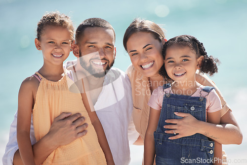 Image of Family, happy at the beach and smile out in the sun while they enjoy and love to spend quality time together. Dad and mom hug kids, they bond and have fun on summer vacation in portrait.