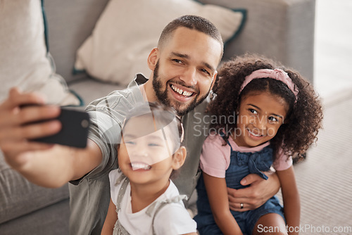 Image of Father taking a selfie on his phone with his children hugging and bonding in their family home. Multicultural father and daughters smiling, happy and taking a picture on their smartphone together