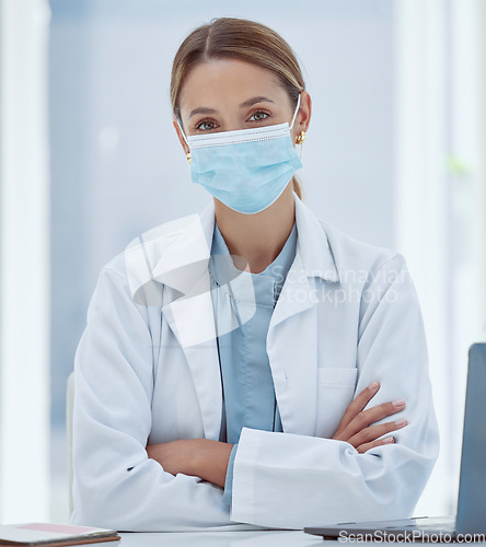 Image of Face mask, covid and portrait of medical doctor in her office at the hospital during pandemic. Coronavirus, woman and healthcare professional sitting at desk in consultation room at medicare clinic.