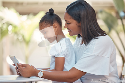 Image of Mother, girl and tablet streaming cartoon, video or education game for children while sitting outdoor. Latin woman and her young daughter watching funny children movie online with technology