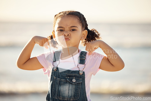 Image of Beach, summer and little girl pulling funny face and flexing on holiday in Mexico. Strong, courage and child at ocean on vacation in Cancun. Waves, sea and sand, healthy kid in nature on school break