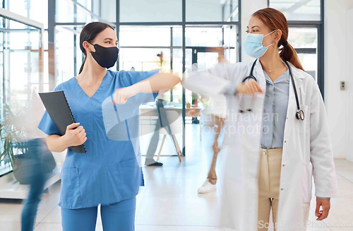 Image of Covid healthcare doctor and nurse greeting with elbow in hospital clinic. Medical women or people with face mask and social distancing in corona virus pandemic for trust, motivation and innovation