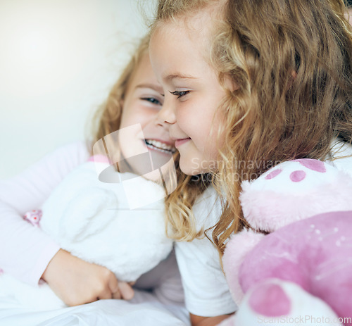 Image of Children, love and twin sisters playing together holding teddy bear toys while lying comfortable sharing family or sibling bond at home. Happy, family and caring girls and friends in bed for fun