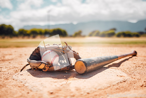 Image of Baseball, sport and empty with a bat, ball and mitt on a base plate on a pitch outdoor after a competitive game. Fitness, sports and still life with exercise equipment on the ground for training