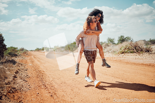 Image of Couple, love and travel with a man and woman walking on a sand road in the dessert or nature together. Summer, romance and dating with a happy, young male giving a piggyback to a female in the wild