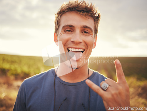 Image of Man, hands and portrait of rock sign for travel tour or vacation in the countryside and nature outdoors. Happy, excited young male traveler, rocker or musician with hand gesture and tongue out