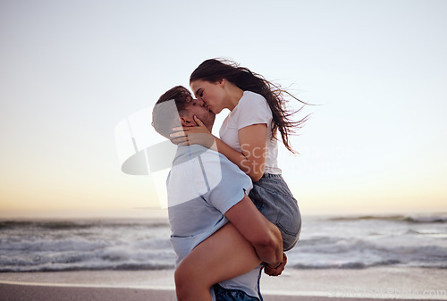 Image of Love, couple and kiss on beach at sunset for romantic and passionate embrace on summer evening date. Dating USA woman and man enjoy dusk sky together at Los Angeles ocean with physical affection.