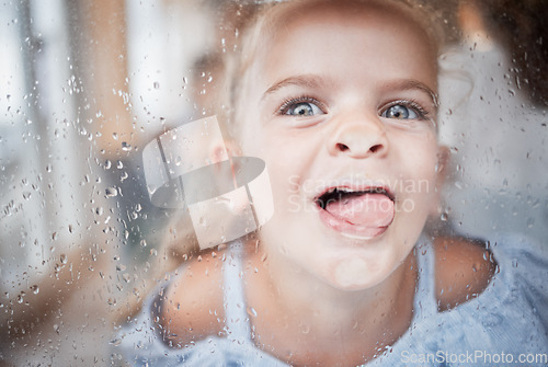 Image of Funny, kid and tongue on window portrait with goofy and enthusiastic face pressed on surface. Young, happy and crazy girl child enjoying playful lick on glass with rain droplets closeup.