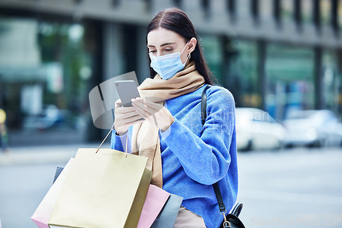 Image of Woman, shopping in covid mask with smartphone, communication about sale or discount at retail mall. Young shopper in pandemic, bags and contact car service for travel and buyer with urban background.