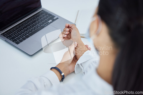 Image of Business woman with a wrist injury, pain or accident from typing or stress sitting by a desk in her office. Girl with muscle sprain, inflammation or carpal tunnel with medical emergency at workplace.