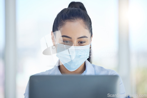 Image of Covid, business and woman reading on laptop while working in an office at work. Corporate employee with email on computer, typing proposal and doing search on the internet with face mask at a company