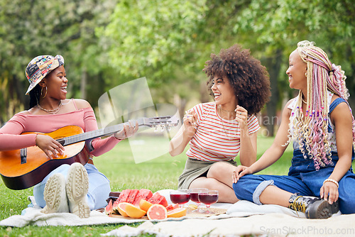 Image of Music, comic and friends on picnic in a park with food and singing with a guitar together in summer. Funny, playful and African women with smile for musician, instrument and lunch on grass in nature