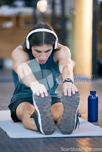 Image of Man, music headphones or stretching on mat in gym workout, training or exercise for wellness, health or cardio. Personal trainer, sports and fitness person listening motivation radio podcast on break