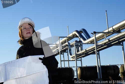 Image of Young architect looking at blueprint in front of construction si