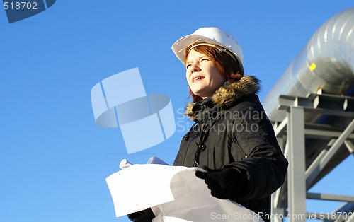 Image of Young architect looking at blueprint in front of construction si