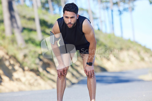 Image of Fitness, exercise and tired with a sports man taking a break from his workout, training or running on a road in nature. Health, wellness and breathing with a young male athlete resting during his run