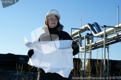 Image of Young architect looking at blueprint in front of construction si