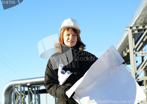 Image of Young architect looking at blueprint in front of construction si