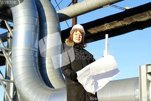 Image of Young architect looking at blueprint in front of construction si