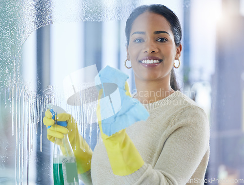 Image of Cleaning, window and water with a black woman washing a glass pane in a home for housework. Portrait, room and apartment with a young female cleaner wiping a transparent surface with a cloth or rag