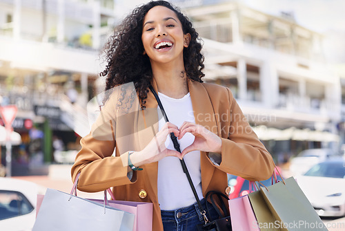 Image of Heart, hands, shopping and woman with smile for retail, fashion and designer sale in the city of Miami. Portrait of a young girl in the street for a market, bags and love for store in the road