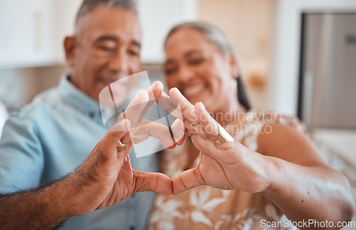 Image of Hands, heart and love with a senior couple in their retirement home together for health, wellness and romance. Fingers, sign and affection with a mature man and woman pensioner bonding in their house