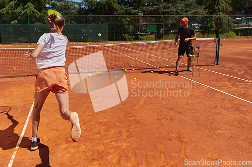 Image of A professional tennis player and her coach training on a sunny day at the tennis court. Training and preparation of a professional tennis player